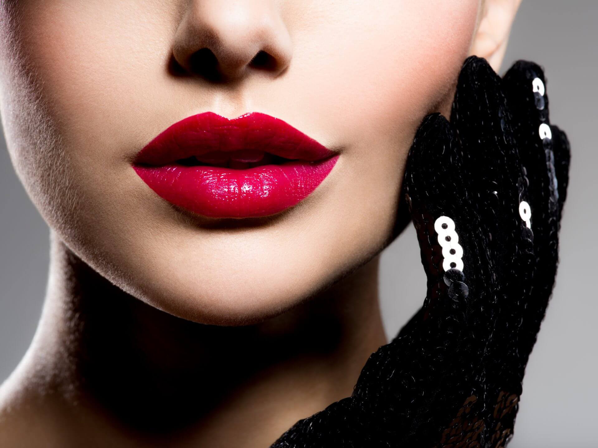 Close up of woman with plump lips, red lipstick and black gloves